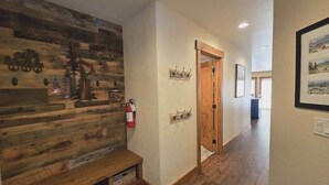 A hallway with wooden walls, a bench, a fire extinguisher, and a door leading to another room. - Golf Course Getaway w/ Patio, Near Beach & Skiing (McCall)