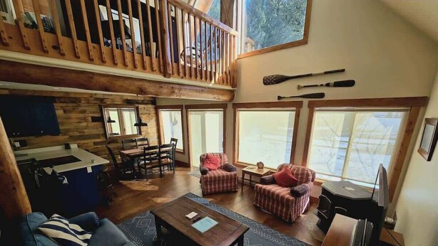 A spacious living area with a wooden floor, a sofa, a coffee table, and a TV. - Golf Course Getaway w/ Patio, Near Beach & Skiing (McCall)