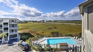 Ein Hotel mit Pool, Blick auf eine Wiese und einem Parkplatz.