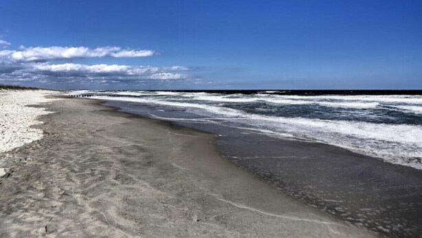 Ein Strand mit blauem Himmel und Wellen.