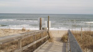 Una passerella in legno che conduce alla spiaggia, con vista libera sull'oceano.