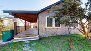 Una casa vacanze con un portico coperto, un patio in legno e un piccolo giardino.