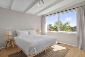 A bedroom with a bed, two bedside lamps, a window with curtains, and a view of trees. - Casa Piccolo - Peninsula Hot Springs 5 mins away (Rye)