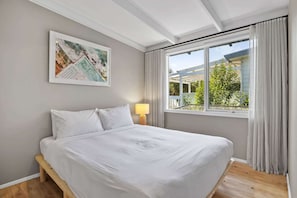A neatly made bed with white linens, a single bedside lamp, and a framed map on the wall. - Casa Piccolo - Peninsula Hot Springs 5 mins away (Rye)
