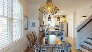 Een moderne keuken met een centraal eiland, roestvrijstalen apparatuur en een hanglamp.