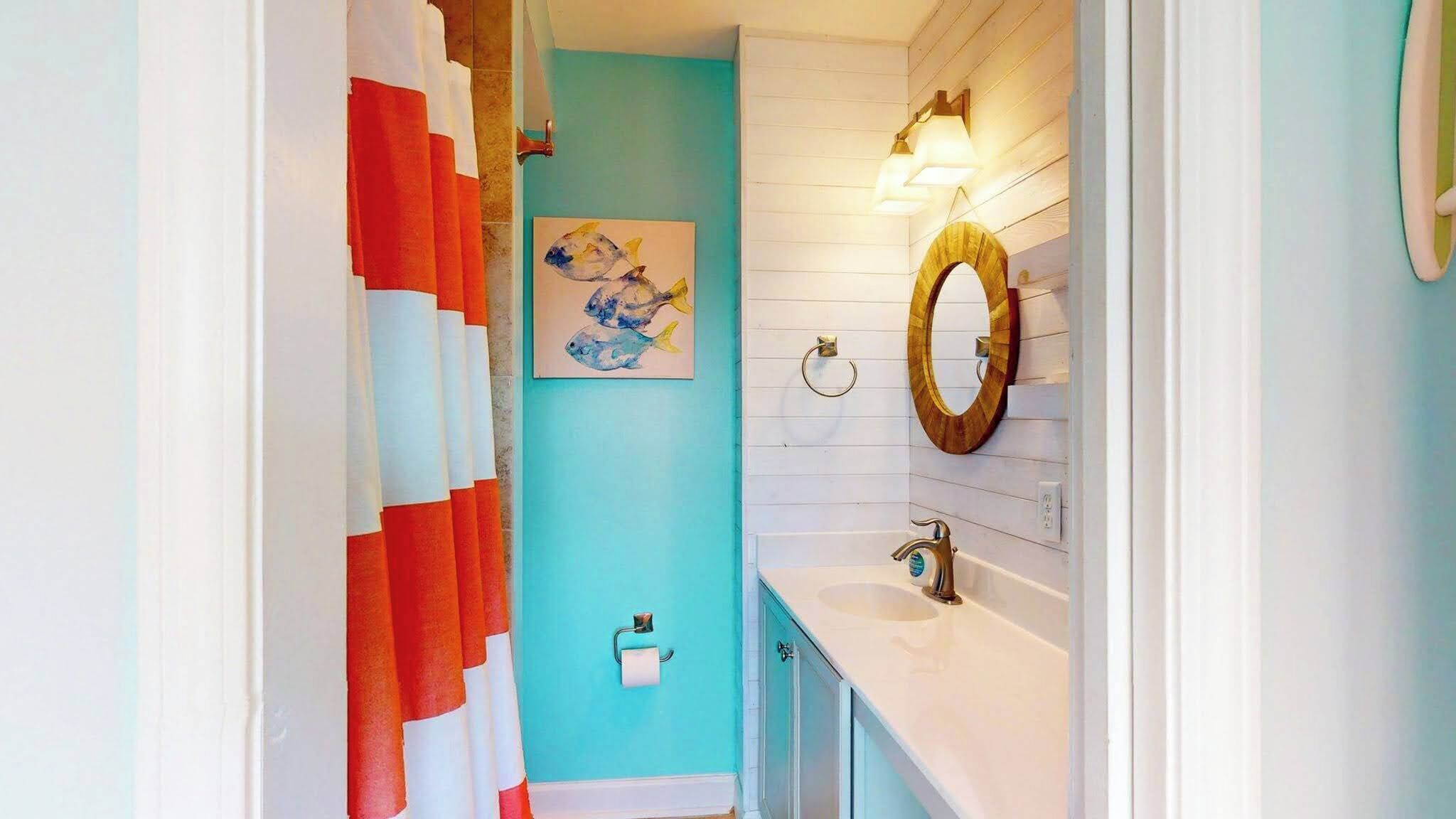 A bathroom with a turquoise wall, white vanity, and a wooden-framed mirror.