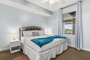 A neatly arranged bedroom with a bed, bedside tables, and a large window with curtains. - Trendy lake condo w/Disney view (Orlando)