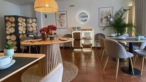 A dining area with a round table, chairs, a hanging light fixture, and a wall with a circular shelf. - Hotel Residencial Dora (Braga)