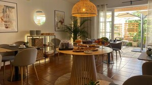 A dining area with a round table, chairs, a hanging light fixture, and a view of the outdoors. - Hotel Residencial Dora (Braga)