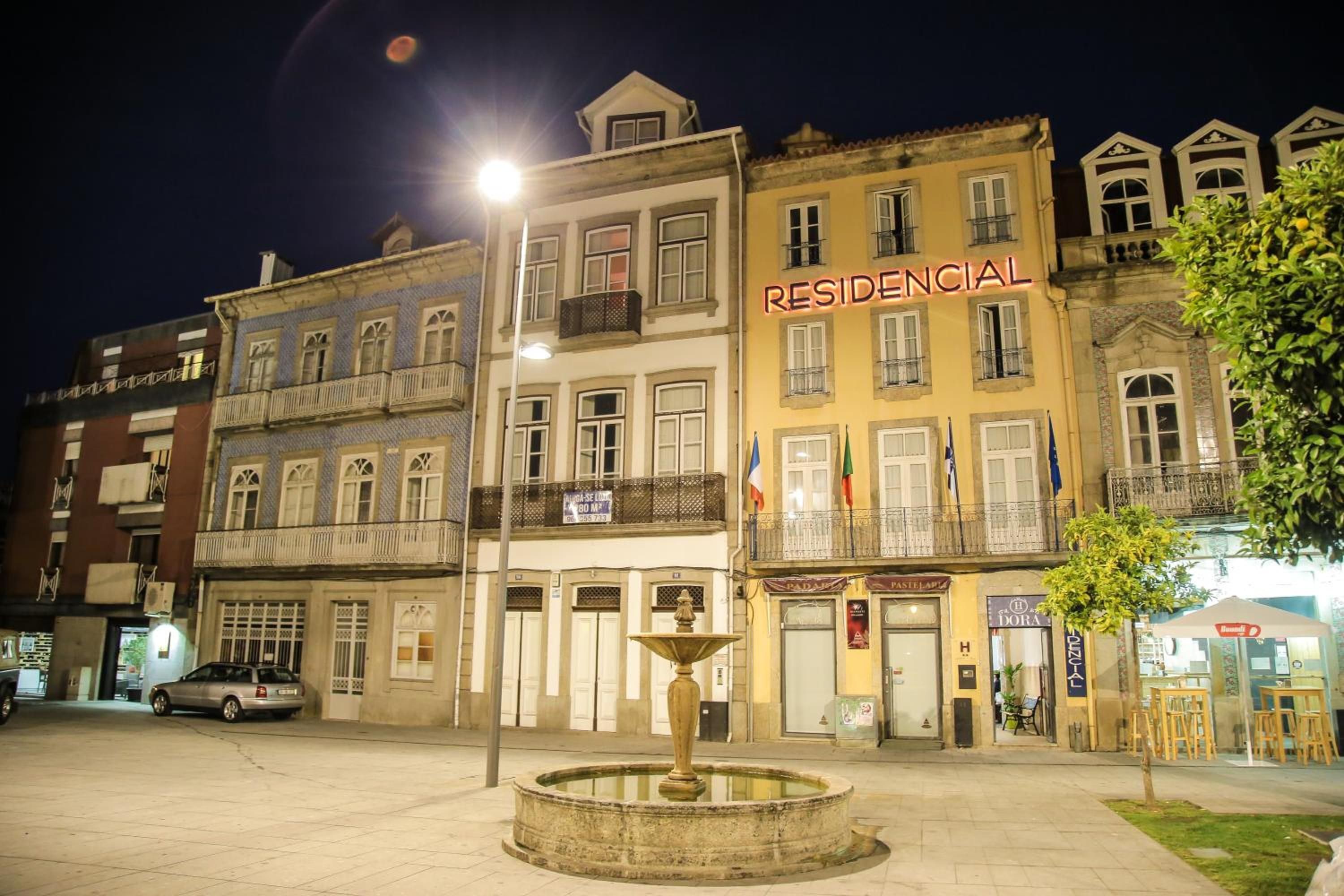 Un edificio con un letrero que dice 'RESIDENCIAL' y una fuente al frente.