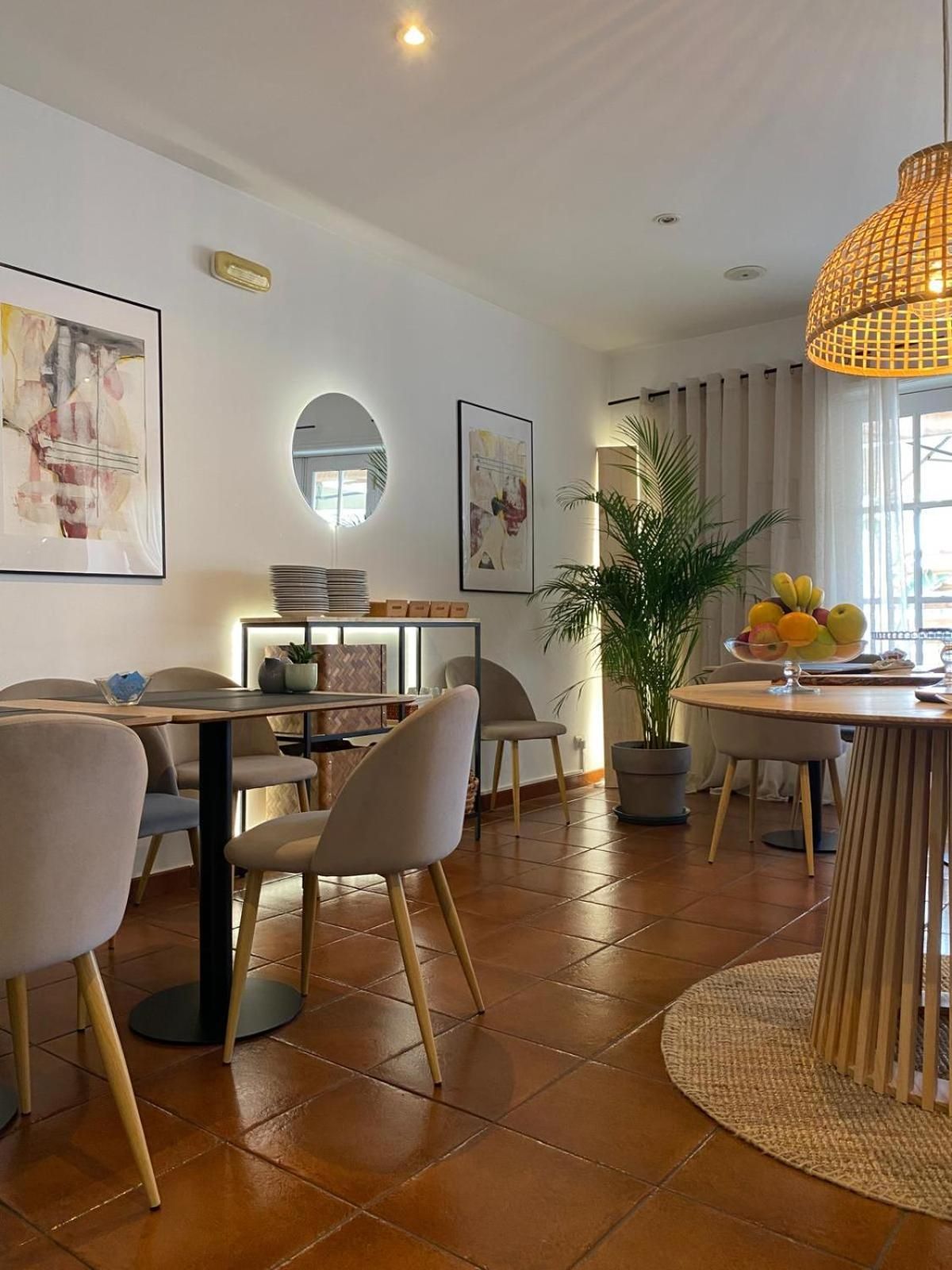 Un espace repas moderne avec une table ronde, des chaises, une plante en pot et des œuvres d’art accrochées aux murs.