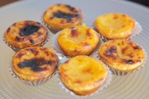 A plate of six egg tarts with a golden-brown crust. - Hotel Residencial Dora (Braga)