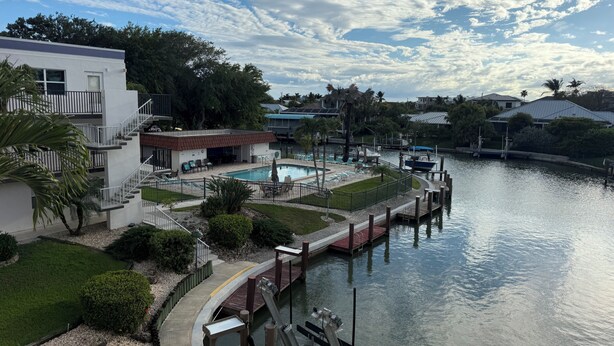 Una propiedad frente al agua con piscina, muelle y un edificio con balcón.