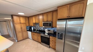 Una cocina moderna con armarios de madera, electrodomésticos de acero inoxidable y suelo de baldosas.