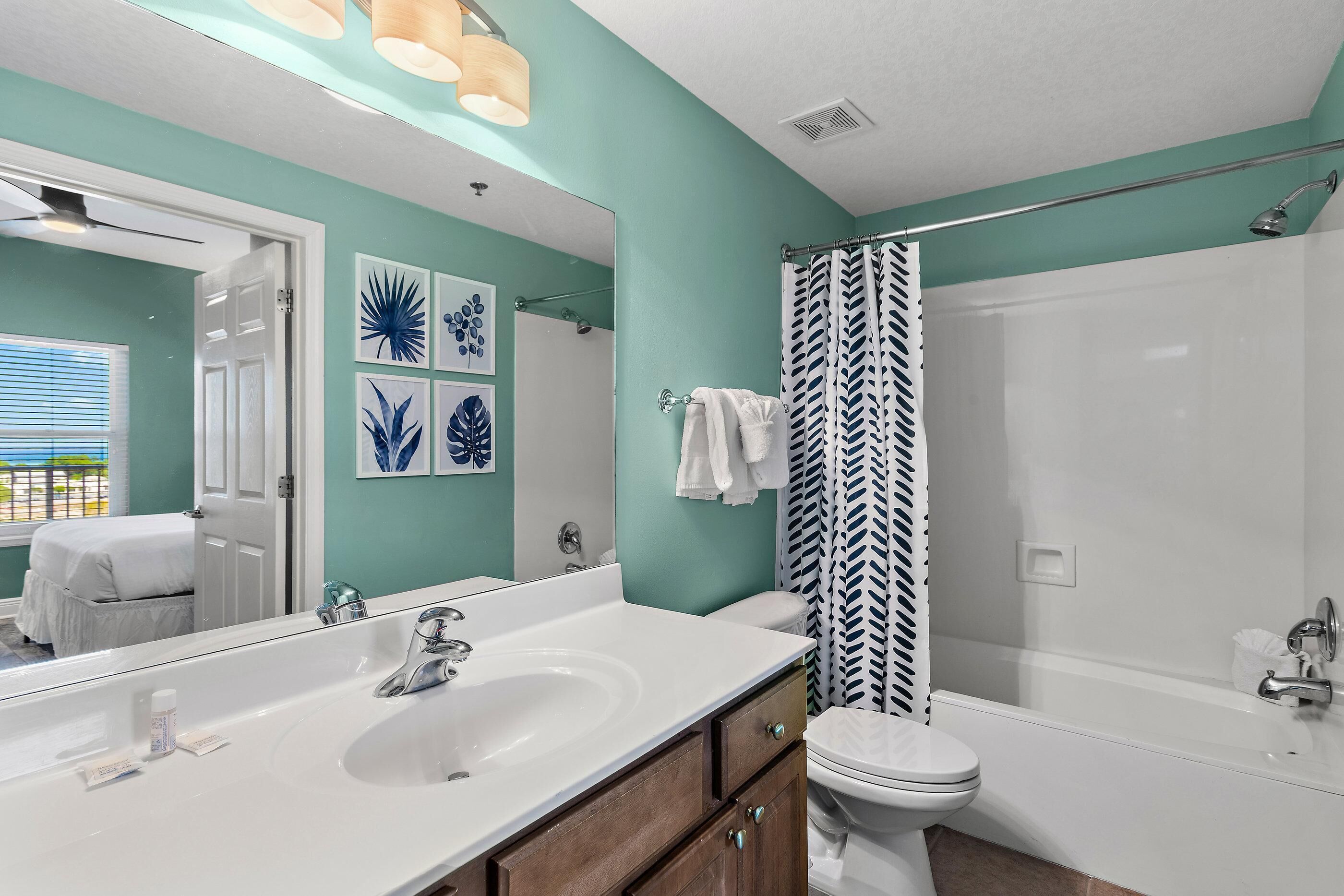A bathroom with a white sink, a toilet, a bathtub, and a shower curtain.