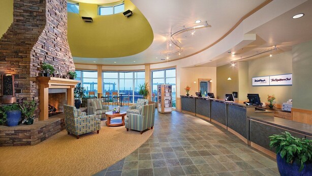 A spacious lobby with a stone fireplace, comfortable seating, a reception desk, and large windows offering a view. - 1-Bedroom Condo on the Ocean in Scenic Seaside with Fitness Room (Seaside)