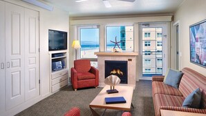 A living room with a fireplace, a television, and a view of the beach. - 1-Bedroom Condo on the Ocean in Scenic Seaside with Fitness Room (Seaside)
