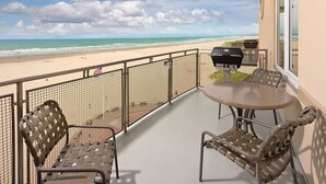 A balcony with a view of the beach, a table, and two chairs. - 1-Bedroom Condo on the Ocean in Scenic Seaside with Fitness Room (Seaside)