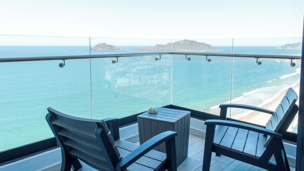 A balcony with two chairs and a small table, overlooking a beach and the sea. - Sky & Sea View (Mazatlán)