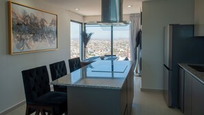 A modern kitchen with a central island, a dining area with a view, and a large painting on the wall. - Sky & Sea View (Mazatlán)
