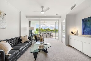 Ein modernes Wohnzimmer mit einem schwarzen Ledersofa, einem Glastisch und einem Essbereich mit Stühlen und einem Tisch.