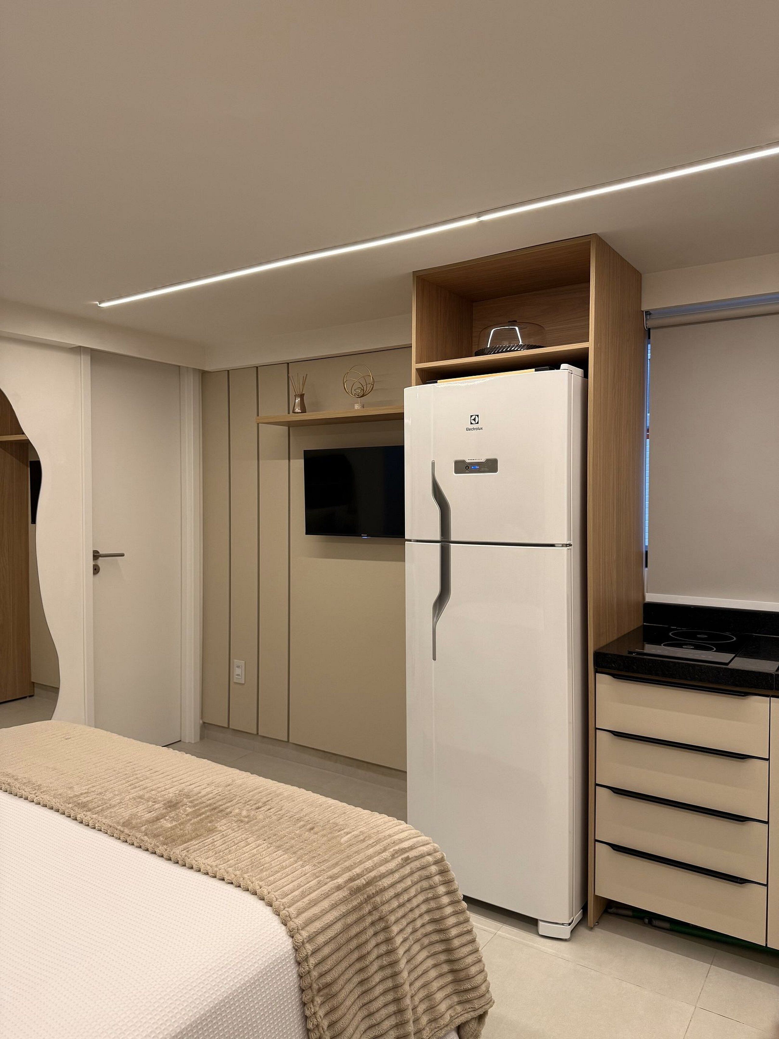 A compact kitchen with a built-in refrigerator, a microwave, and a stove. There is a small countertop and a cabinet above the stove.