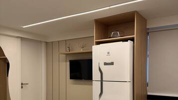 A compact kitchen with a built-in refrigerator, a microwave, and a stove. There is a small countertop and a cabinet above the stove.