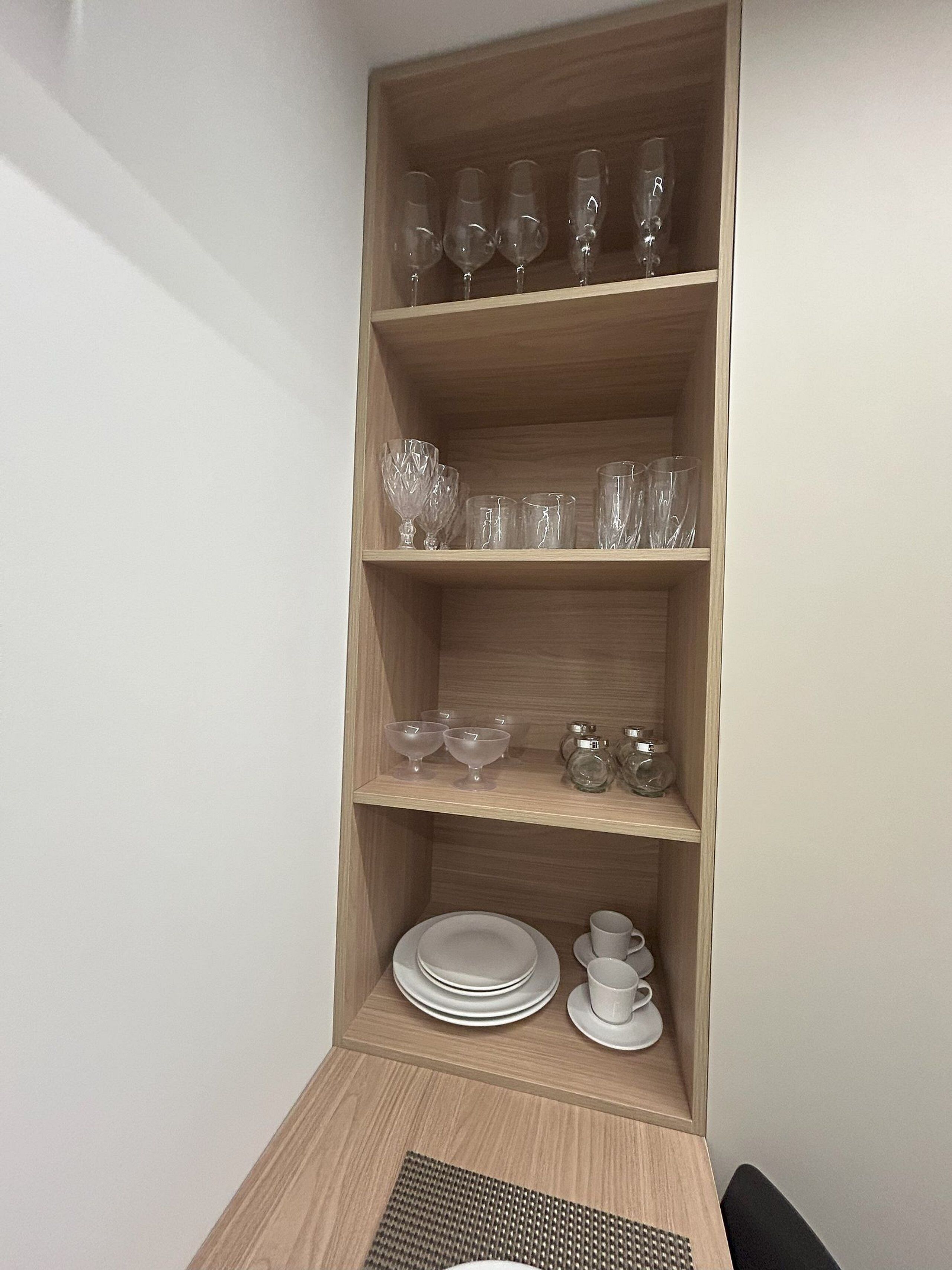 A corner shelf with various glassware and dishes.