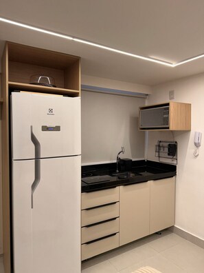 Een moderne keuken met een inbouwkoelkast, een magnetron en een spoelbak.