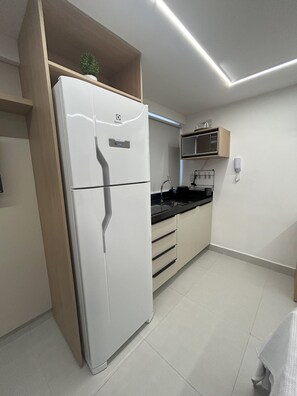 A modern kitchen with a white refrigerator, a microwave, and a sink. - Flat Cabo Branco Aurea 50m do mar 306 (João Pessoa)