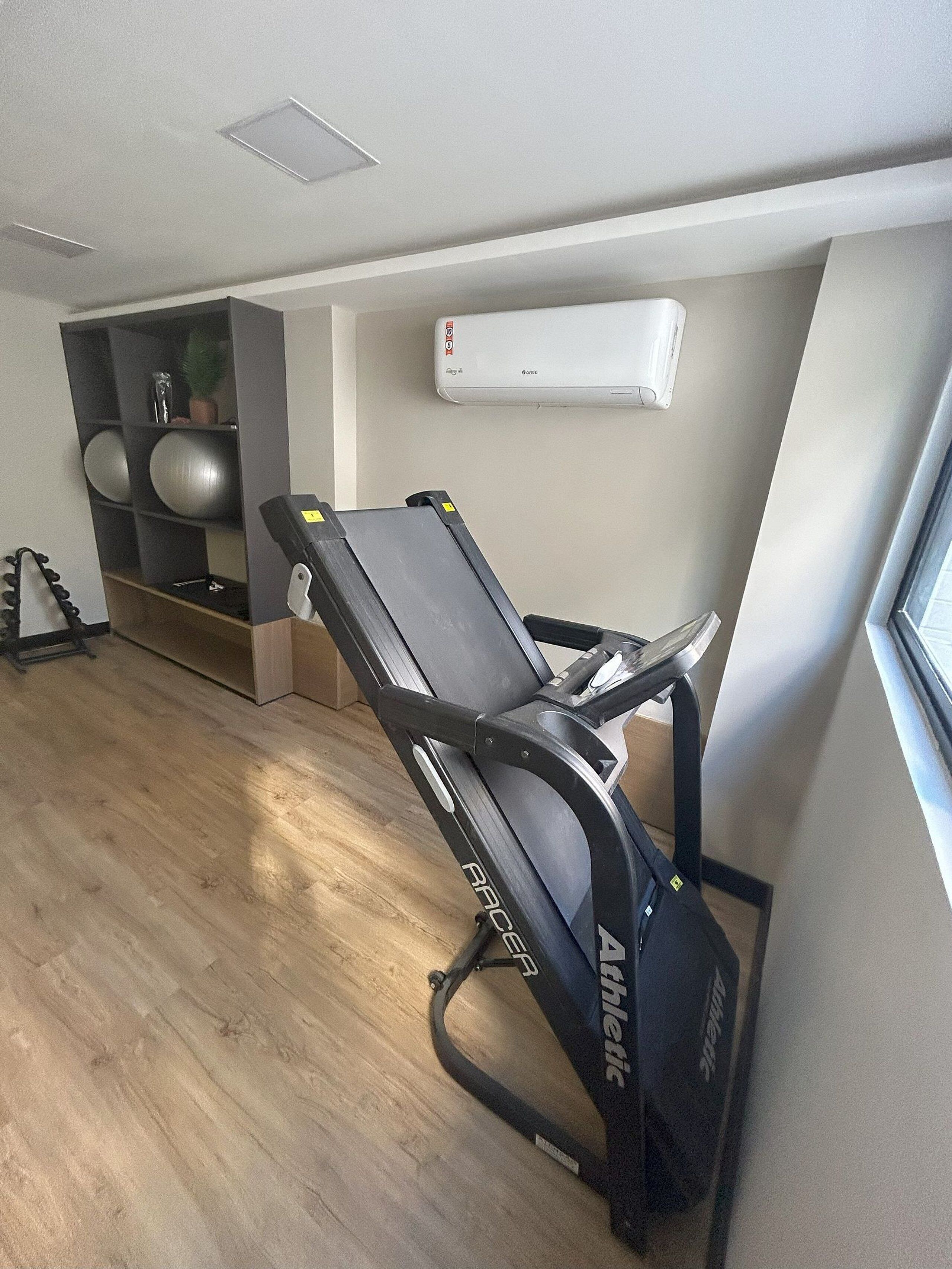 A room with a massage chair, exercise balls, and a wall-mounted air conditioner.