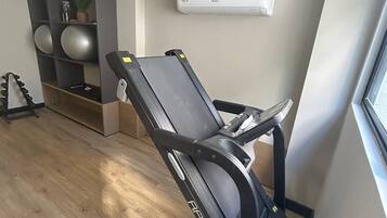A room with a massage chair, exercise balls, and a wall-mounted air conditioner.