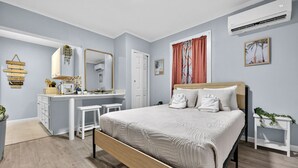 A bedroom with a bed, a vanity with a mirror, and a small desk. - Simple & Comfy Tiny Pensacola Studio (Pensacola)