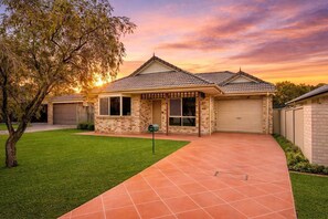 A residential house with a tiled driveway, a well-maintained lawn, and a mailbox.