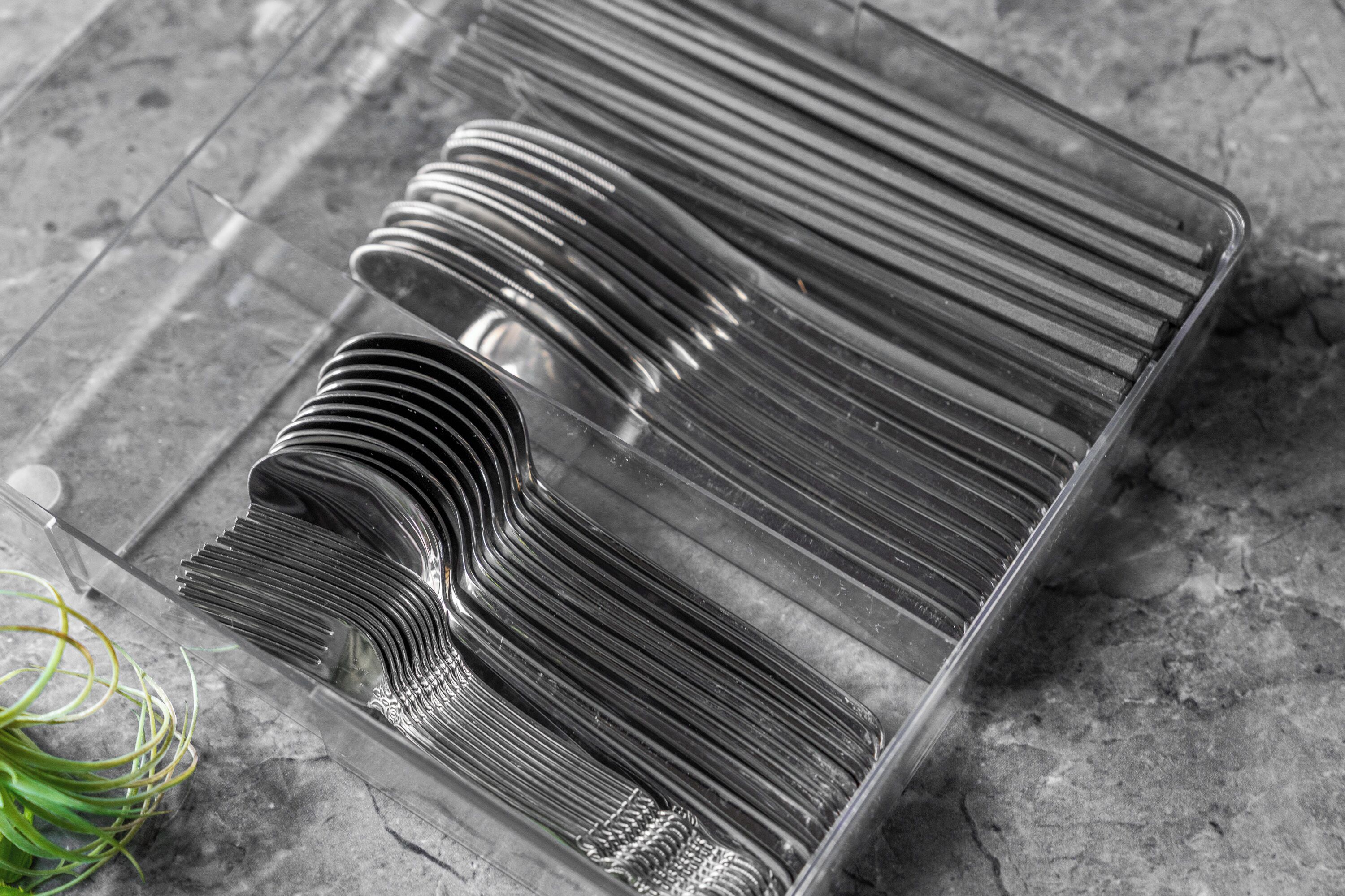 Een transparante plastic lade met netjes opgestapelde metalen spoelen, mogelijk voor industrieel gebruik, op een gestructureerd oppervlak.