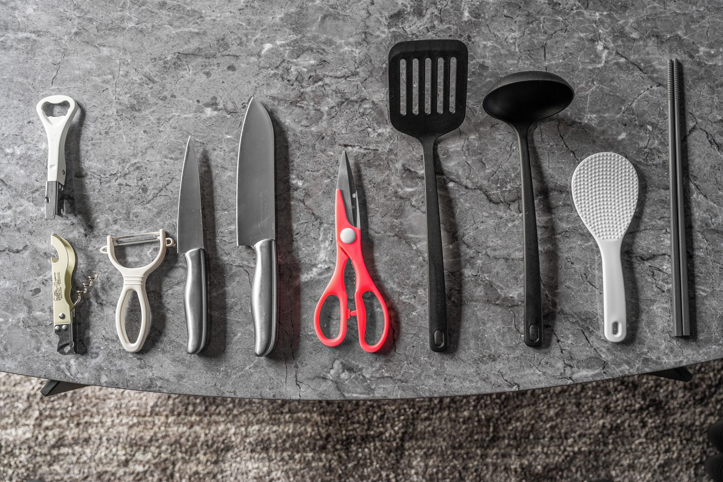 A variety of kitchen utensils laid out on a textured surface.