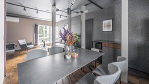 Et moderne spiseområde med et langt bord, grå stole og en vase med blomster.