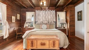 Ein Schlafzimmer aus Holz mit einem Bett, zwei Nachttischen, einem Sessel und einer Bank.