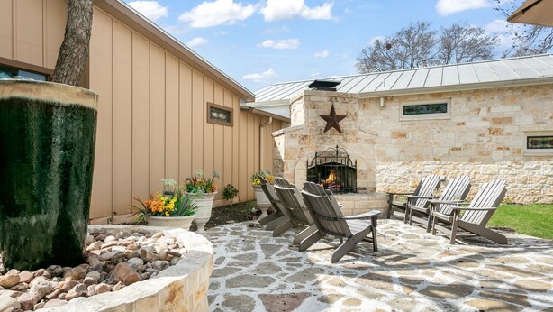 Eine Terrasse mit Steinboden, einem Kamin aus Stein und Sitzgelegenheiten im Freien.