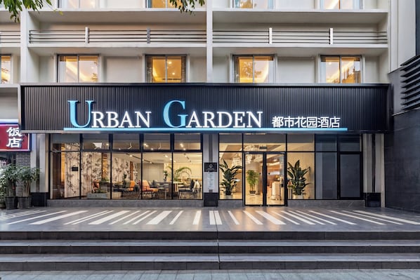 A hotel named "Urban Garden" with a modern facade, large windows, and visible interior seating areas.
