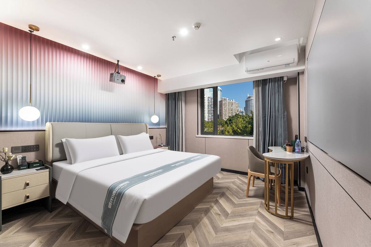 Una habitación de hotel moderna con una cama grande, una mesita de noche y un pequeño escritorio con una silla.