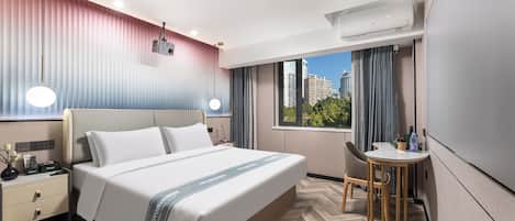 Una habitación de hotel moderna con una cama grande, una mesita de noche y un pequeño escritorio con una silla.