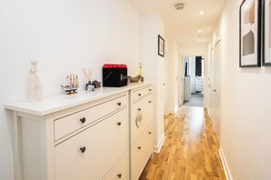 A hallway with a white dresser, a ship model, and a red box. - Modern First Floor Flat with Lift and Balcony (London)