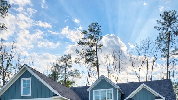 A two-story house with a front porch, a brick entryway, and a well-maintained lawn.