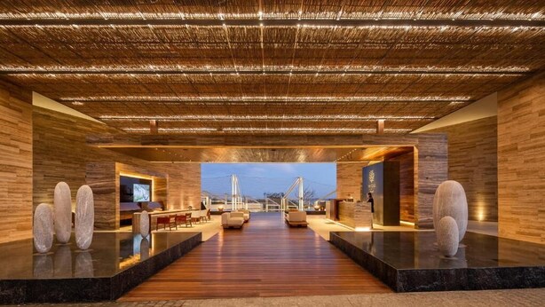 A spacious lobby with a wooden floor, a large seating area, and a television screen. - The Club at Solaz (San José del Cabo)