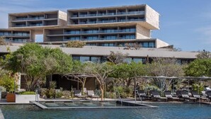 A hotel with a pool area, outdoor seating, and a multi-story building with balconies. - The Club at Solaz (San José del Cabo)