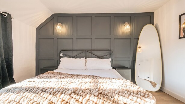 Een slaapkamer met een bed, een surfplank en een wandlamp.