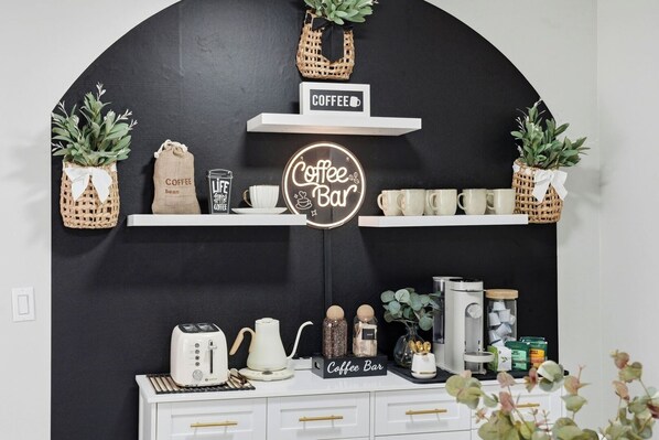 Ein Kaffee-Bereich mit Schild, Kaffeebohnen, einer Kaffeemaschine und verschiedenen Kaffeetassen.