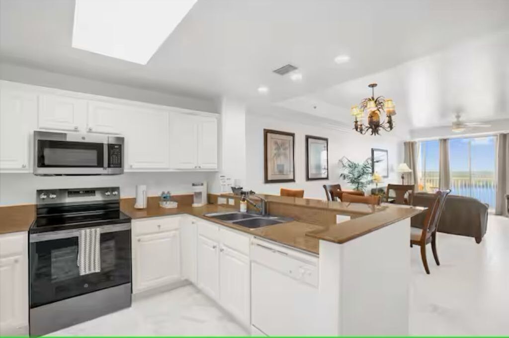 A modern kitchen with white cabinetry, a built-in microwave, and a large island with a sink.