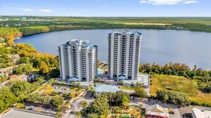 Um hotel com torres altas, um estacionamento e um lago ao fundo.